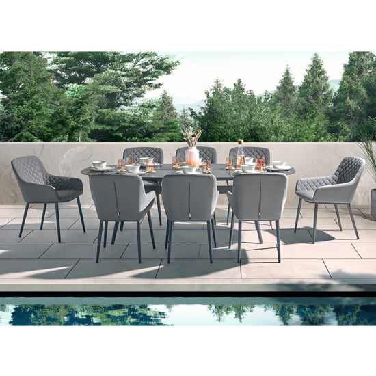 Photo of Arica outdoor oval wooden dining table with 8 grey armchairs